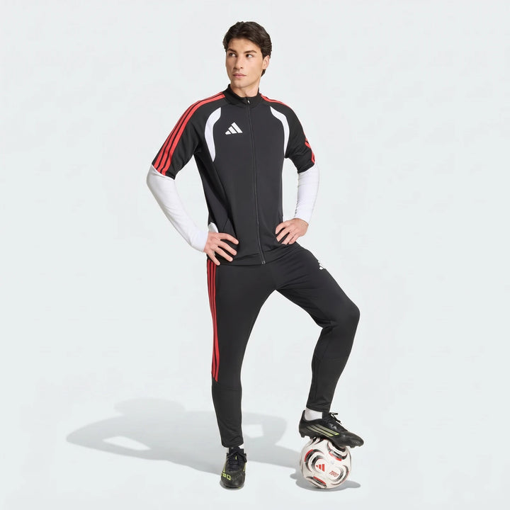 Full body shot of a male soccer player wearing a black, red, and white Adidas Tiro 26 Competition Training Jacket and