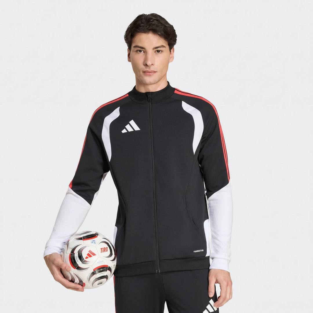 Male model wearing a black, red, and white Adidas Tiro 26 Competition Training Jacket, holding a soccer ball.