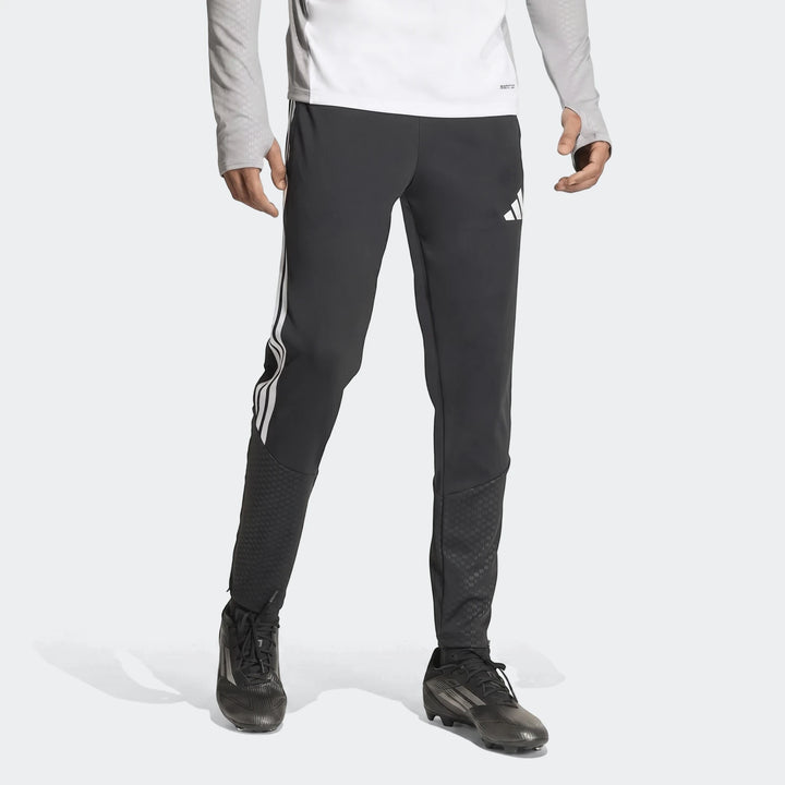 Men's black Adidas Tiro 26 Competition Training Pants, featuring white stripes and logo, worn by a model with black cleats.