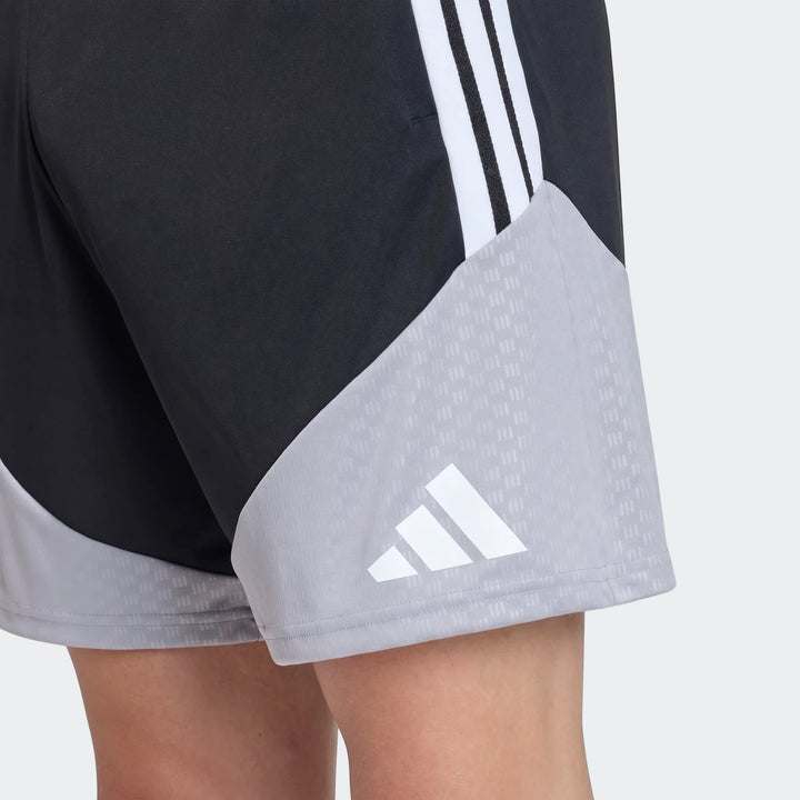 Close-up of black and gray Adidas Tiro 26 Competition Training Shorts with white stripes and logo worn by a person.