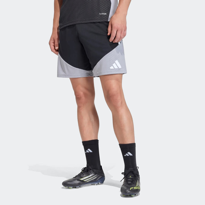 A male model showcases the Adidas Tiro 26 Competition Training Shorts in black and grey, paired with black socks and soccer