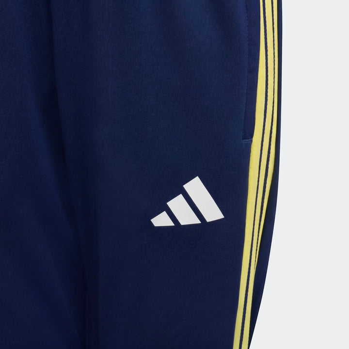 Close-up of Adidas Tiro 26 Competition Youth Training Pants in dark blue with bright yellow three-stripe branding and white