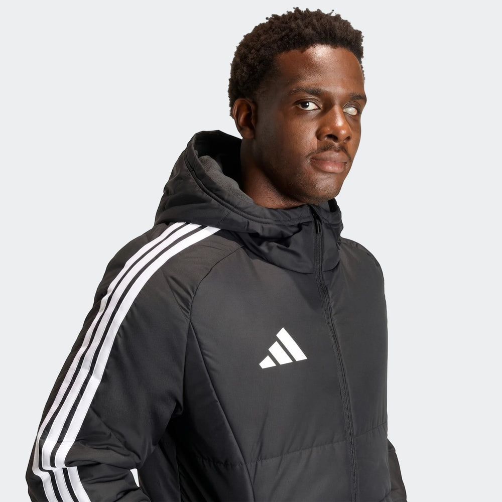 Black Adidas Tiro 26 Long Coat worn by a man, featuring white stripes on the sleeve and Adidas logo on the chest, posed in a