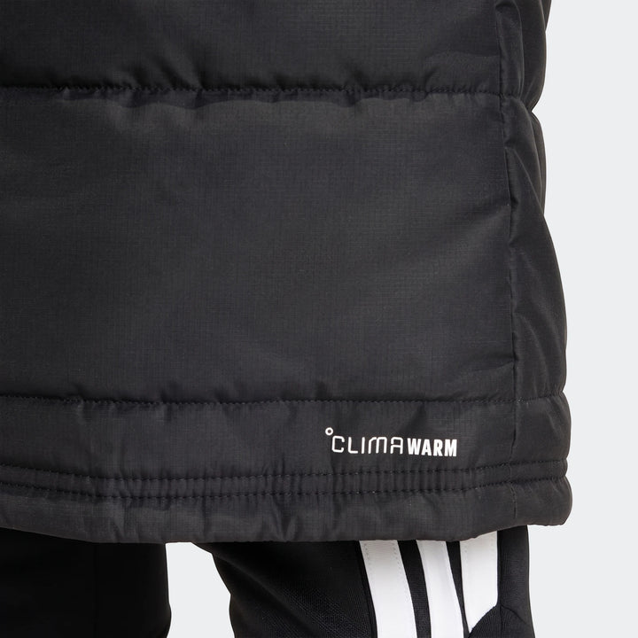 Black adidas Tiro 26 Long Coat, a warm puffer jacket featuring the CLIMAWARM logo, shown worn with black adidas track pants.