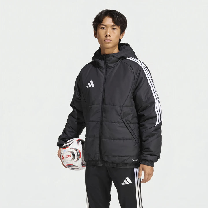 Male model wearing a black Adidas Tiro 26 Windbreaker Jacket and track pants, holding a white soccer ball.
