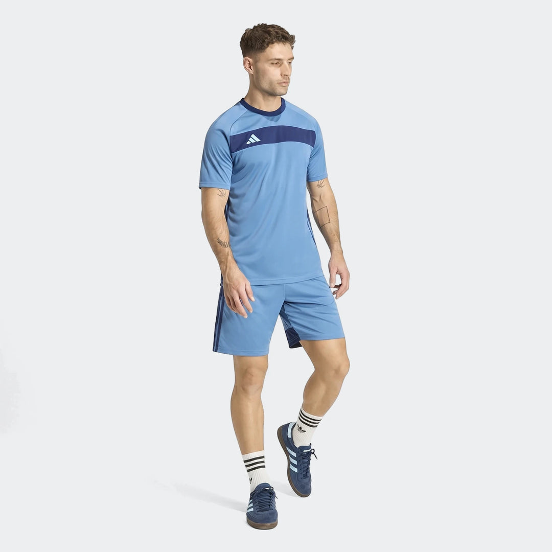 Man wearing light blue Adidas Tiro Essentials shorts and matching t-shirt with blue sneakers and white socks.
