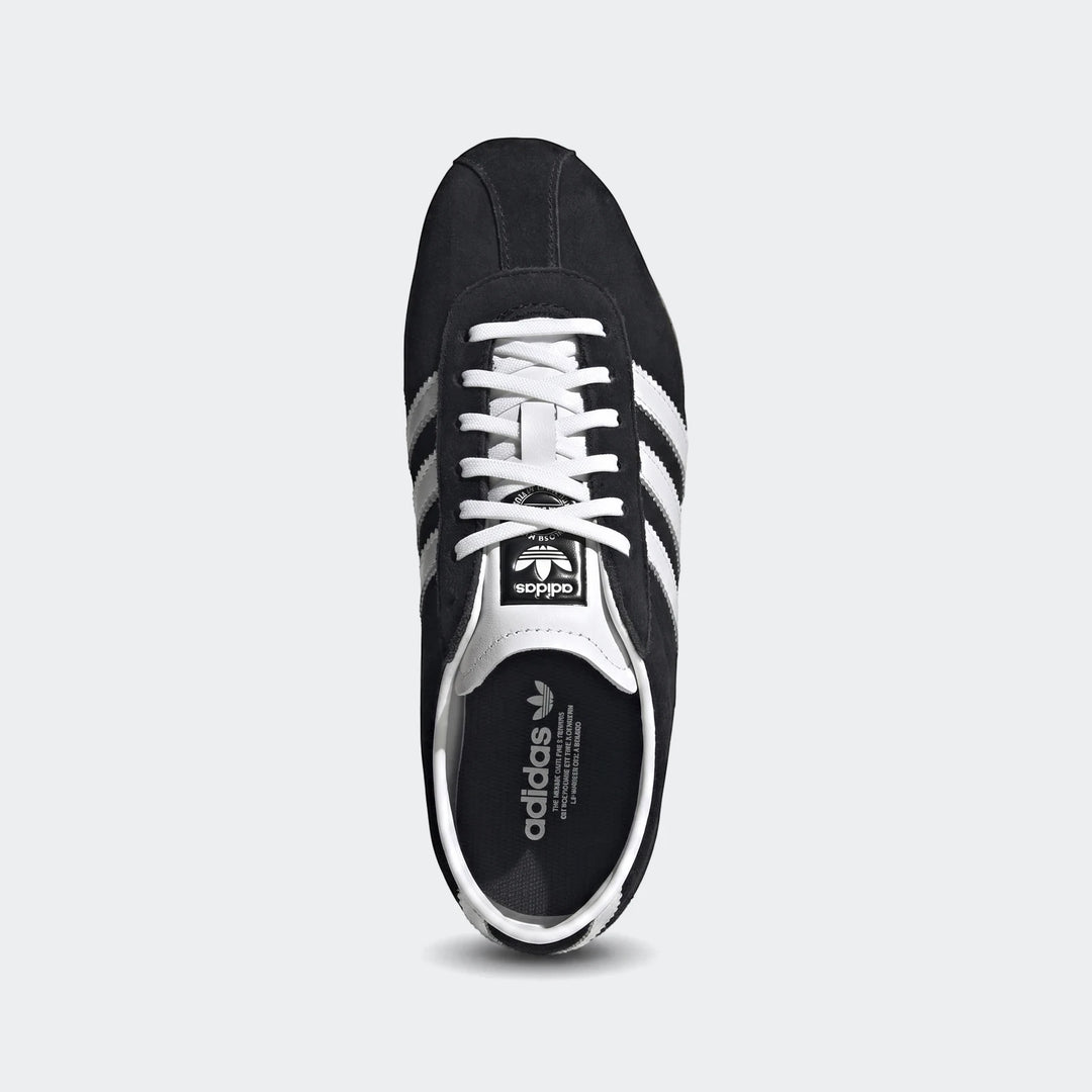 Black Adidas Tokyo shoes with white stripes and laces, crafted from suede, shown in a clean top-down view.