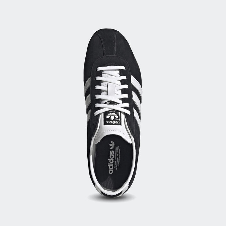 Black Adidas Tokyo shoes with white stripes and laces, crafted from suede, shown in a clean top-down view.