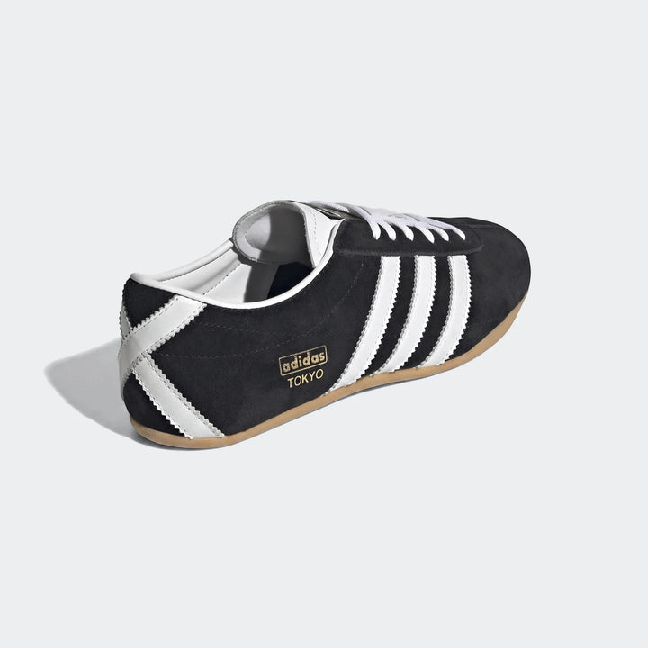 Adidas Tokyo Shoes, black suede upper with white stripes and laces, gold branding, and a gum sole, displayed from a side