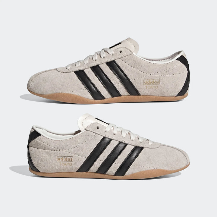 Two pairs of Adidas Tokyo shoes in light gray suede with black stripes, white laces, and gum soles, displayed side by side.