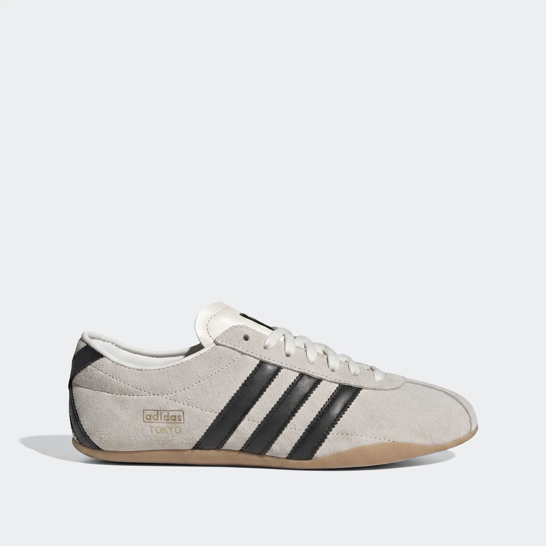 Light grey suede Adidas Tokyo Shoes featuring black leather stripes, white laces, and a gum sole, presented as a classic