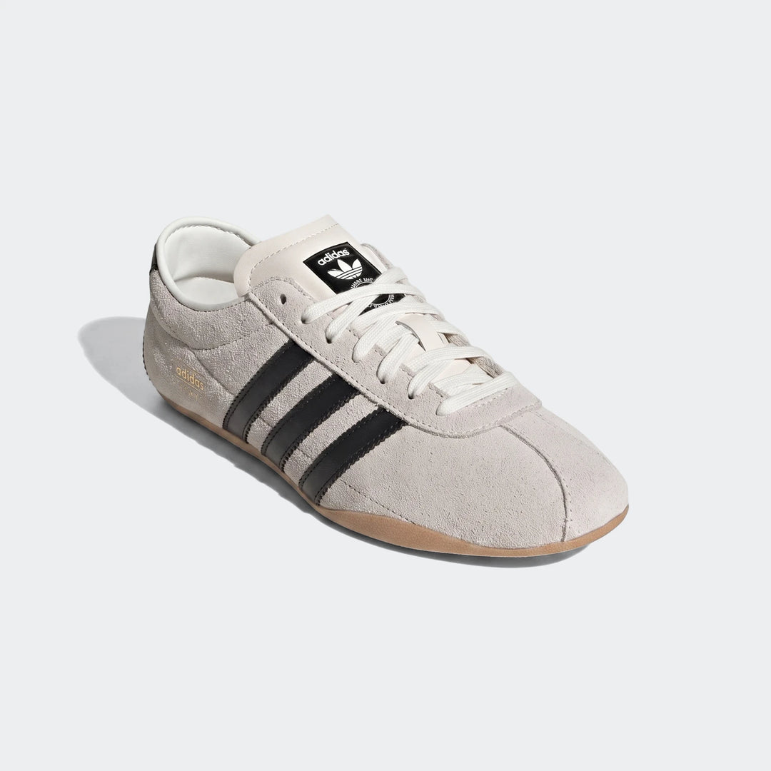 Adidas Tokyo Shoes in light grey suede with black stripes, white laces, and gum sole, viewed from a slightly elevated angle.