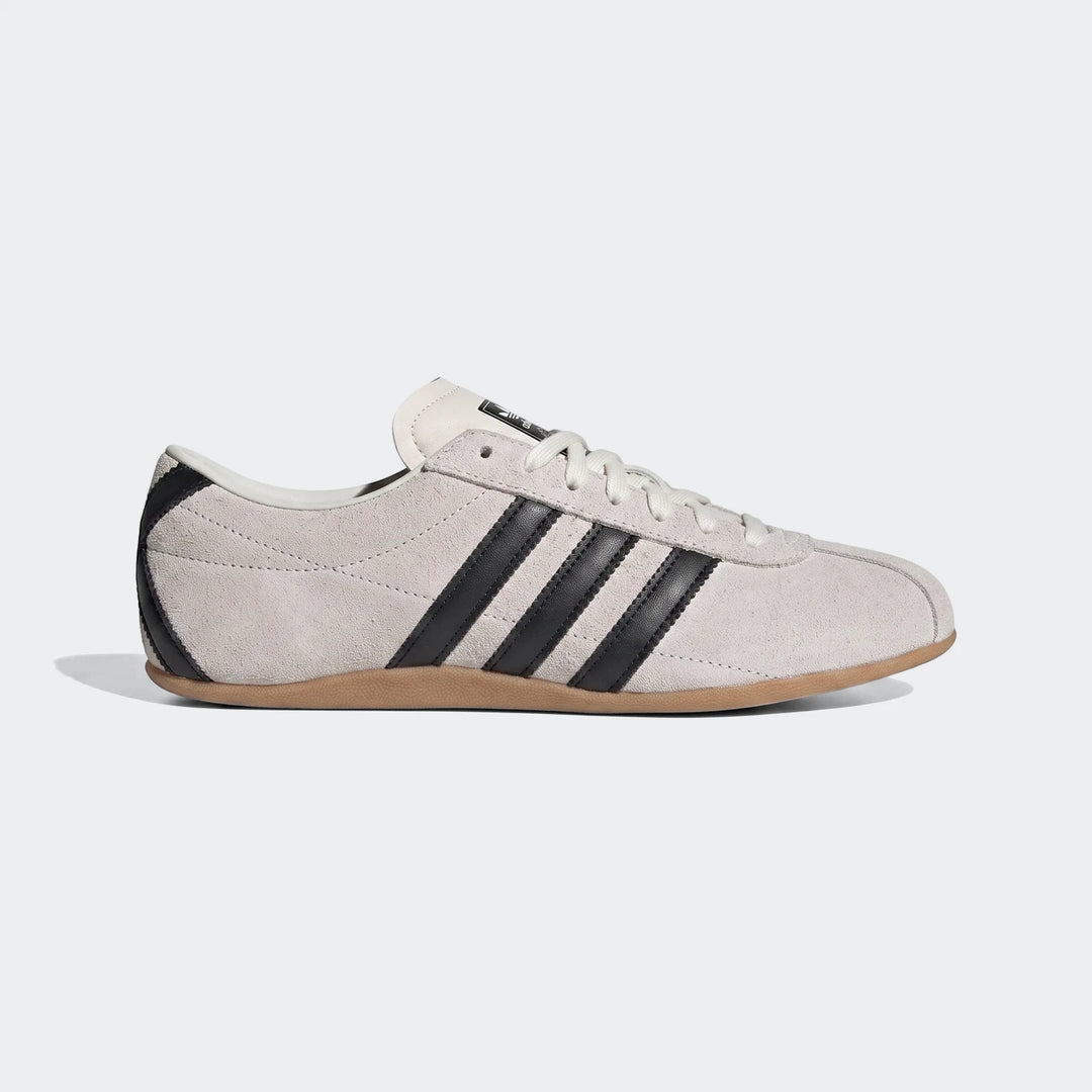 Light grey suede Adidas Tokyo shoes with black stripes and brown gum sole, presented in a side profile view.