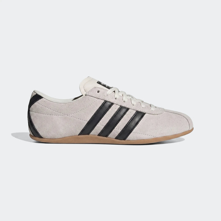 Light grey suede Adidas Tokyo shoes with black stripes and brown gum sole, presented in a side profile view.