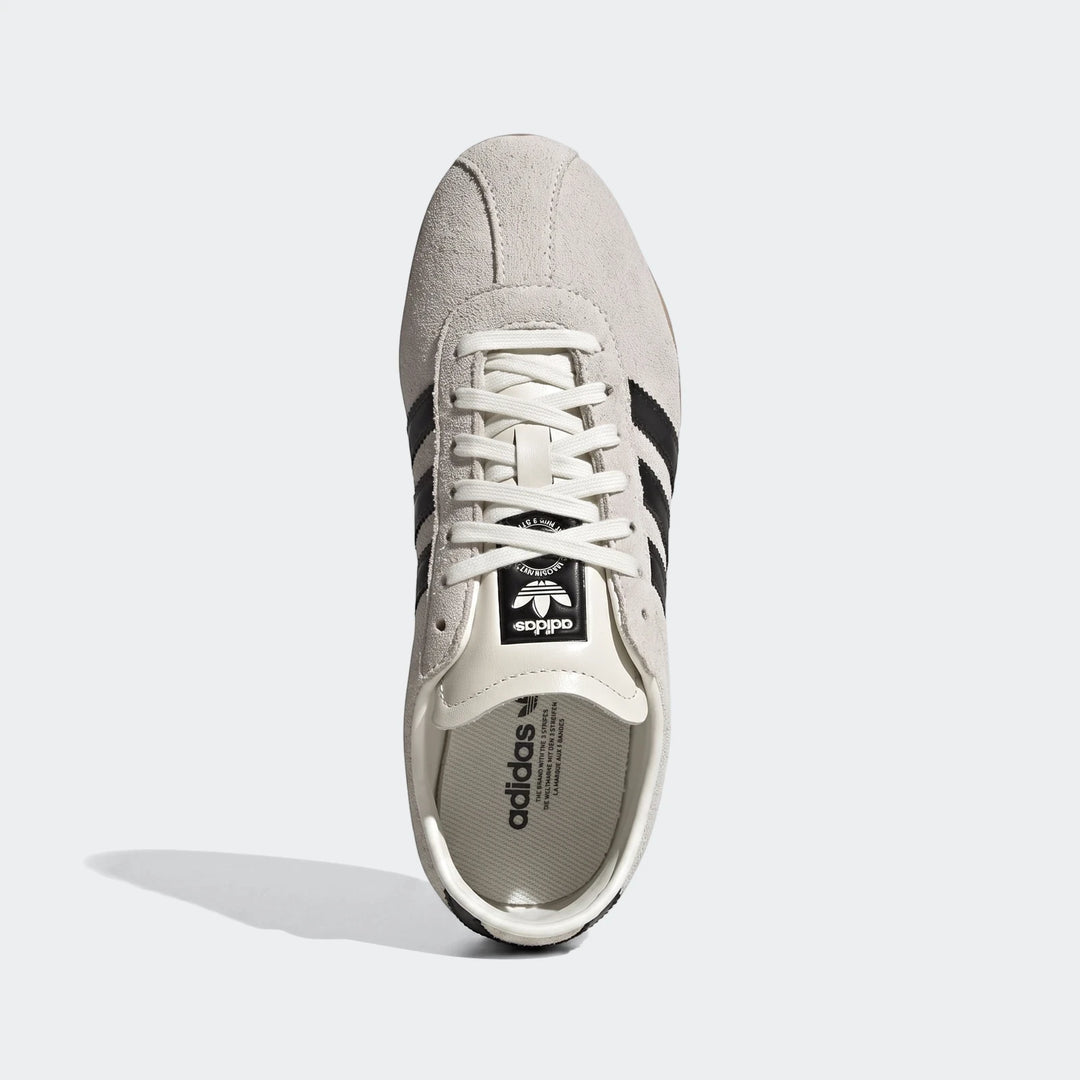 Adidas Tokyo Shoes in light grey suede with black stripes and white laces, viewed from the top down.