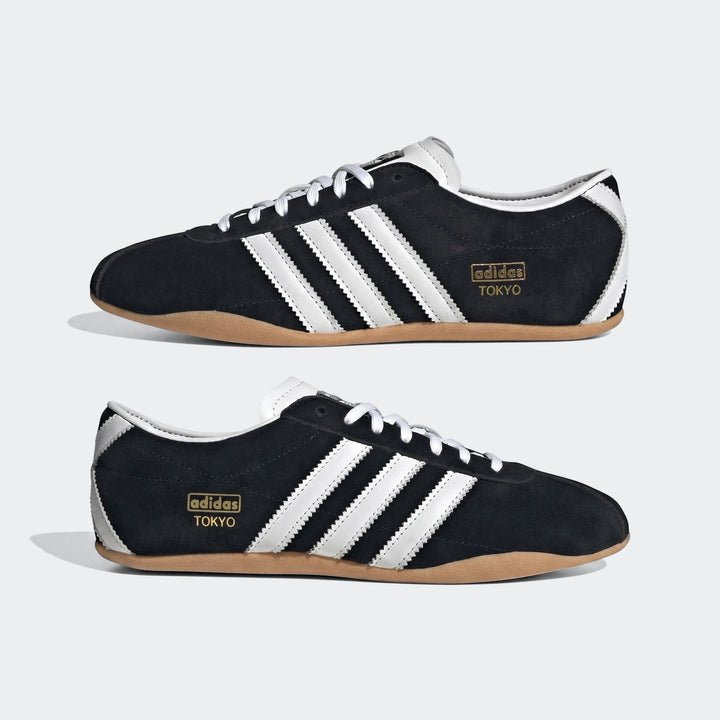Black suede Adidas Tokyo sneakers with white leather stripes, white laces, and gum rubber soles, shown from a side profile.