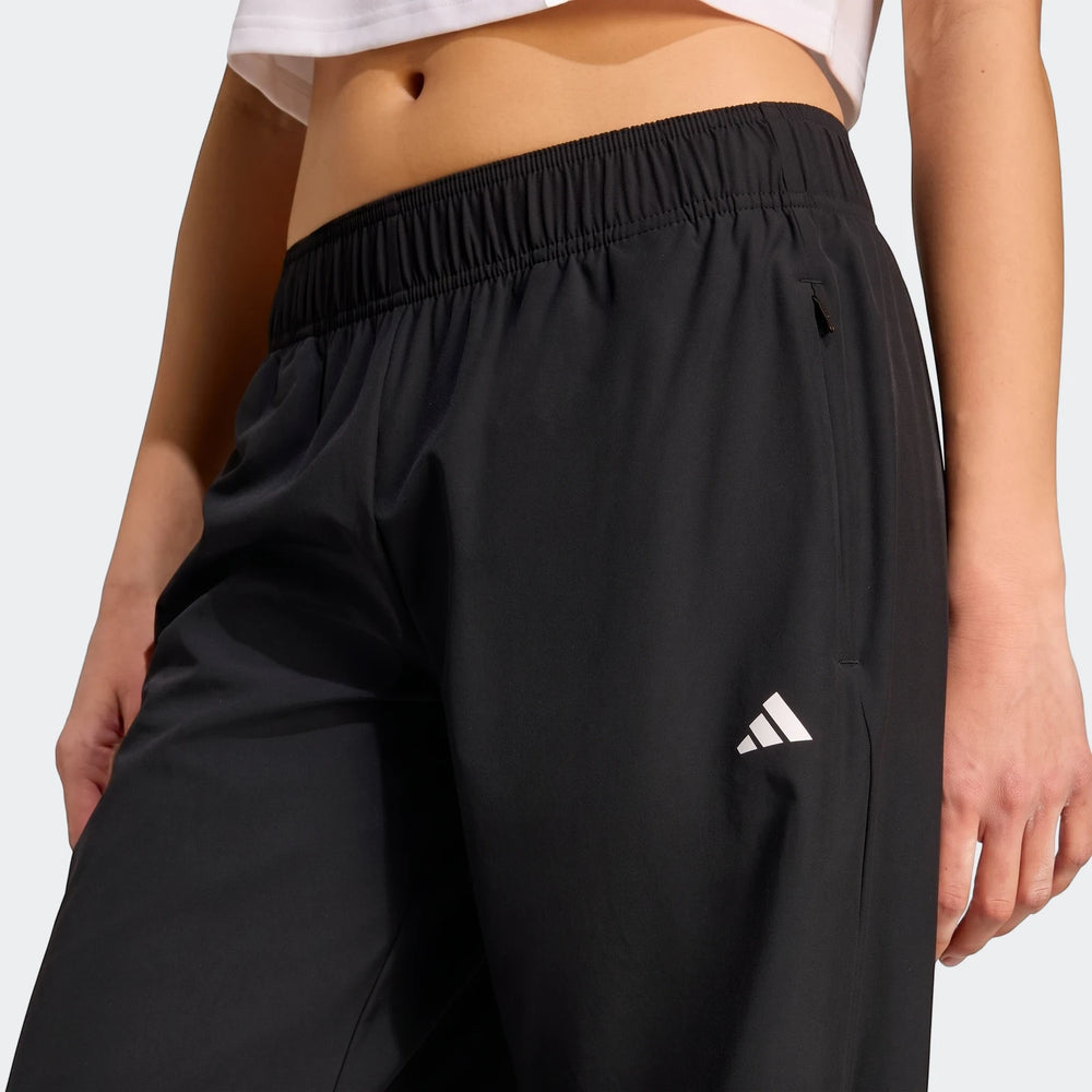 Close-up of a model wearing black Adidas Workout Essentials Woven Training Joggers, showcasing the elastic waistband and