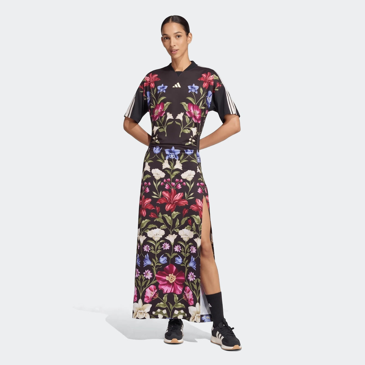 Woman wearing an Adidas x Farm Rio black floral print premium maxi dress with short sleeves, posed full-body.