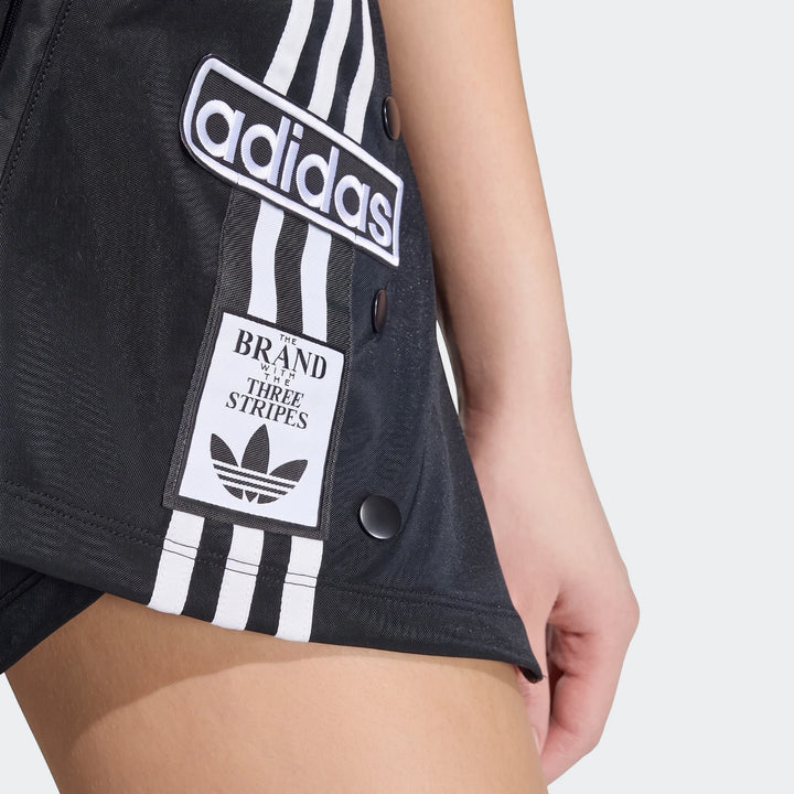 Close-up view of a model wearing a black Adidas X Mia Marquez Mini Skirt with white stripes and logos.
