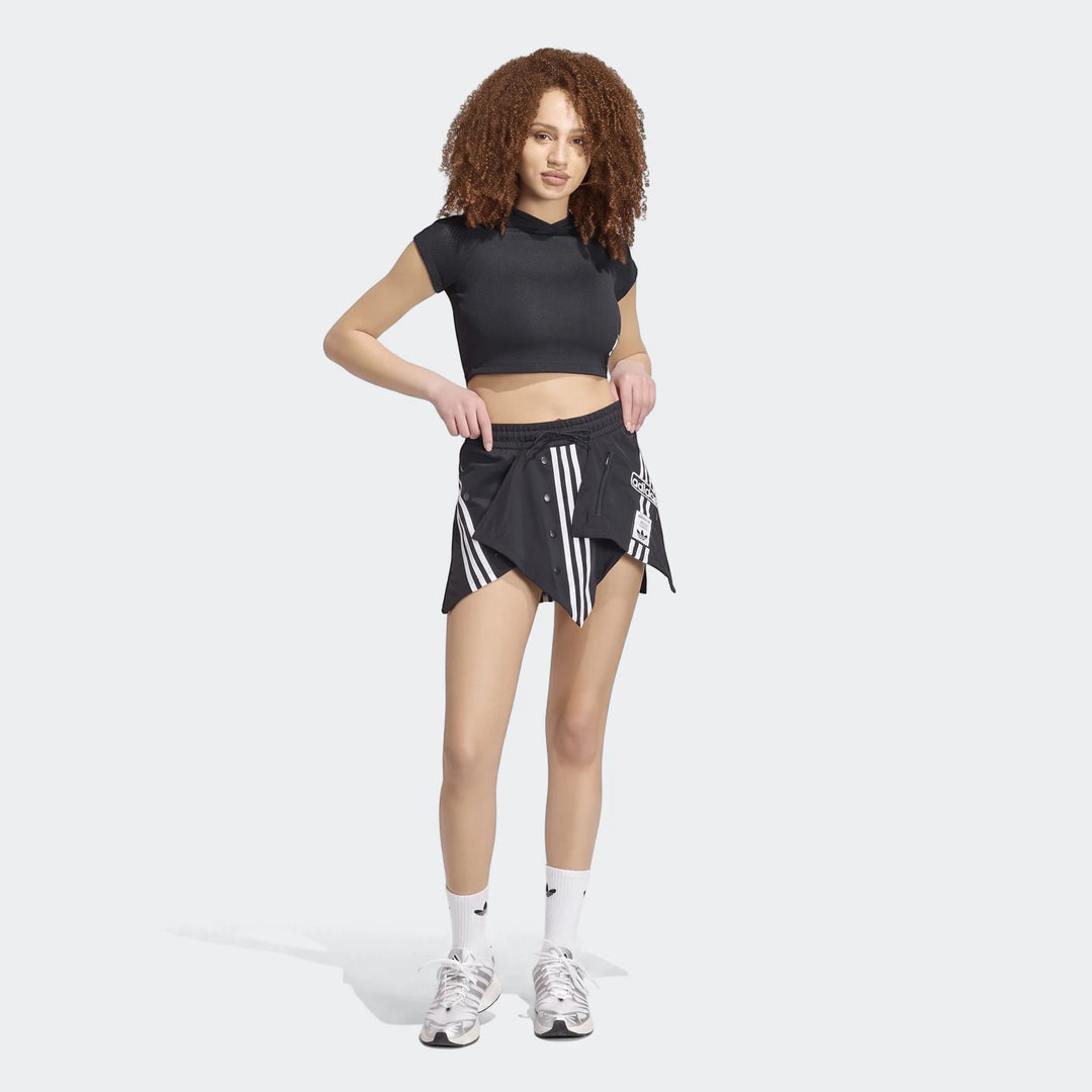 Full-body shot of a model wearing the black Adidas X Mia Marquez Mini Skirt with white stripes, paired with a black cropped