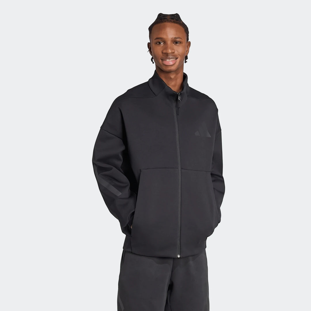 Smiling man wears a black Adidas Z.N.E. full-zip track top, showcasing its design and comfortable fit.
