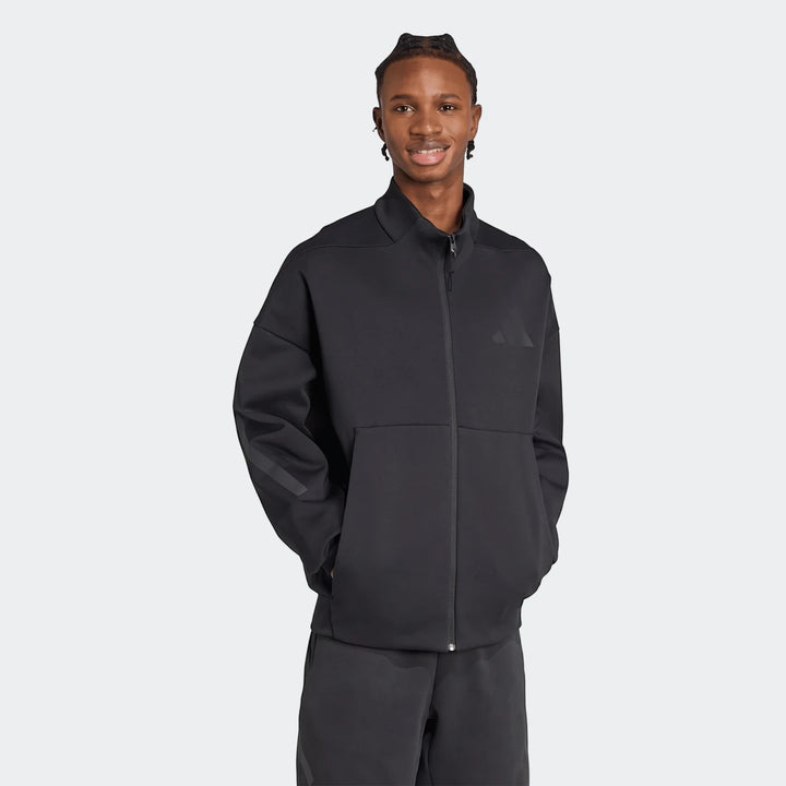 Smiling man wears a black Adidas Z.N.E. full-zip track top, showcasing its design and comfortable fit.