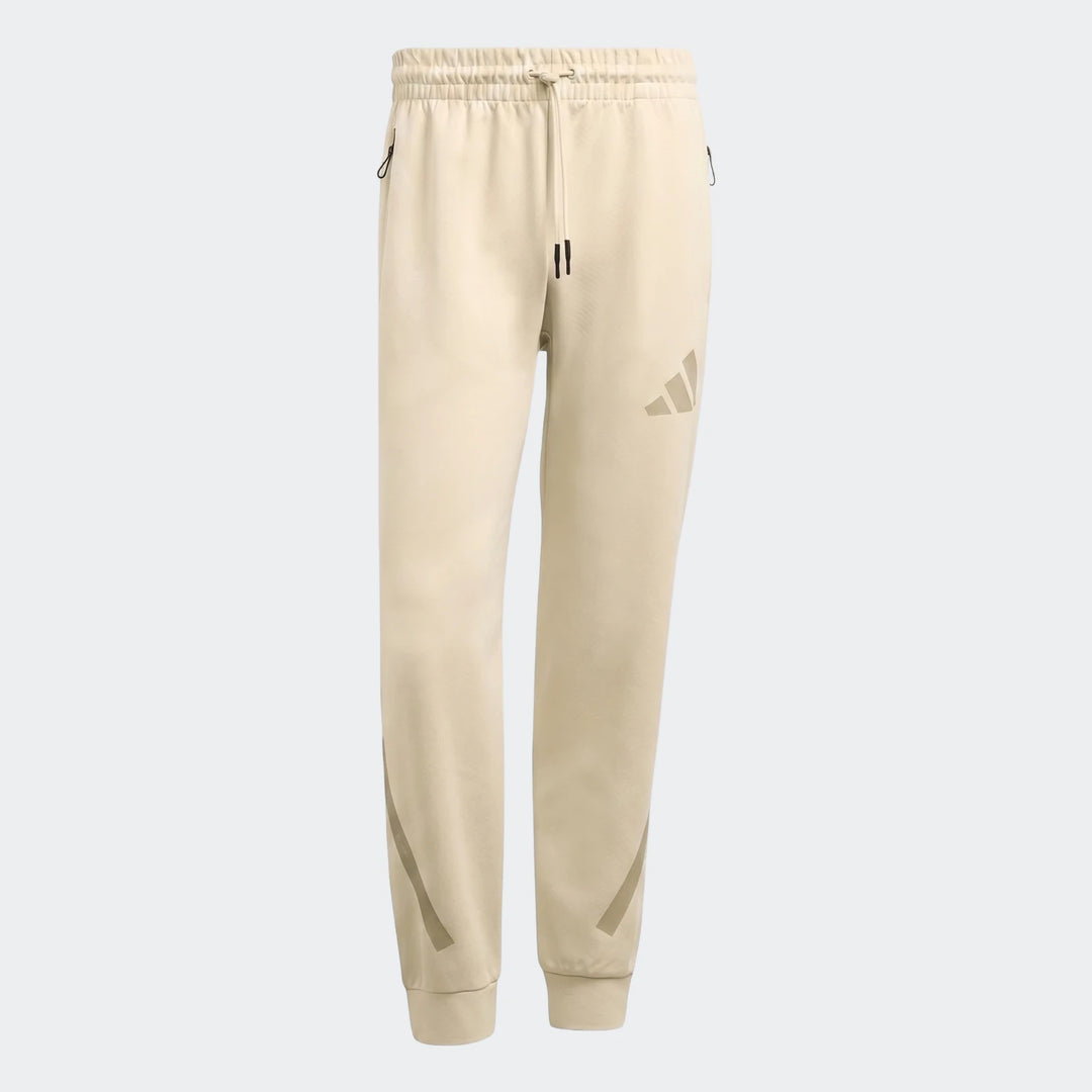 Cream Z.N.E. Track Pants for men, featuring a comfortable fit, drawcord waist, zippered pockets, and subtle branding, shown
