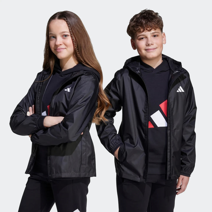 Two children wearing black Adidas Z.N.E. Track Tops with hoodies and track pants, posing for a front view studio shot.