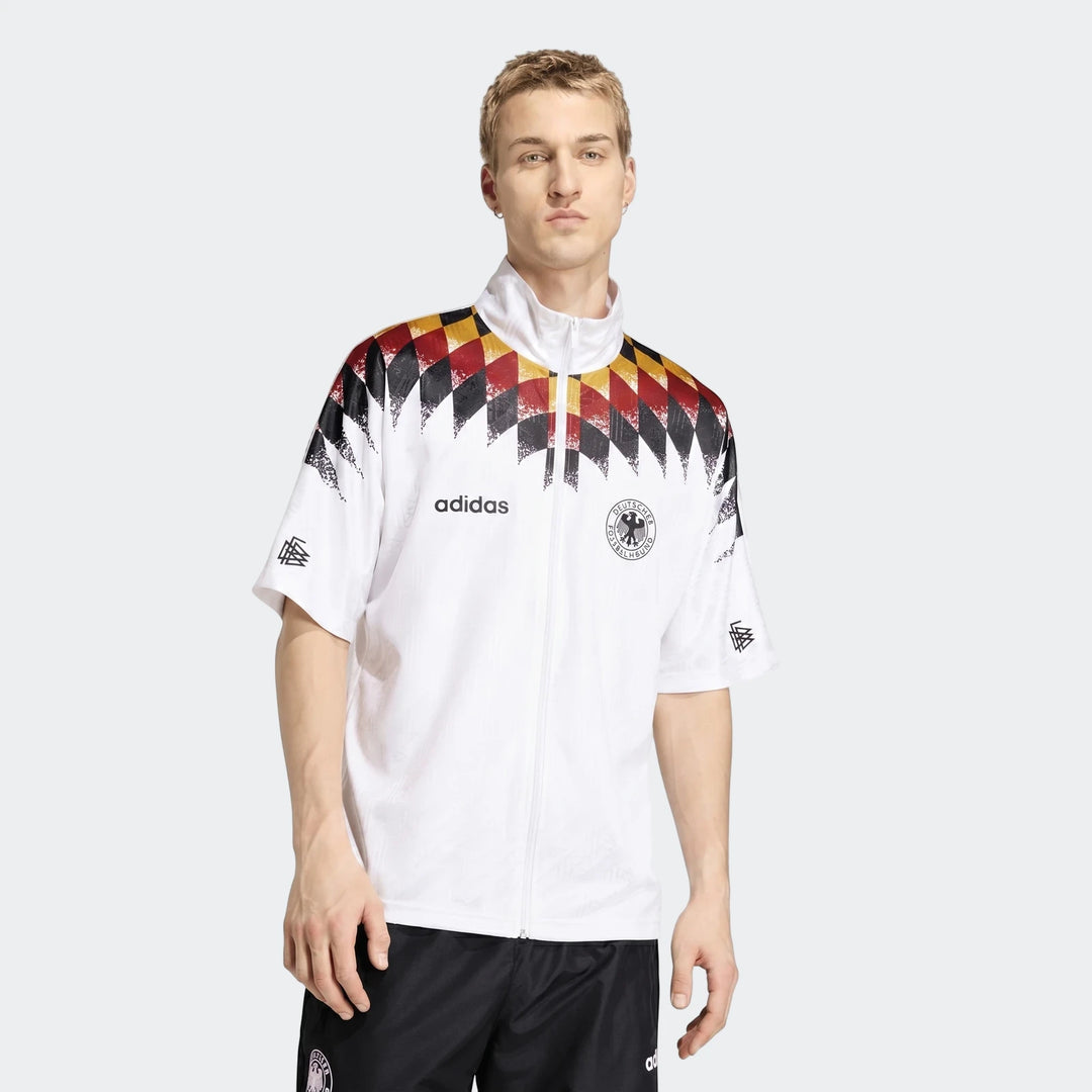 Young man wearing a white Adidas Z.N.E. Track Top with black, red, and yellow diamond pattern, front view.