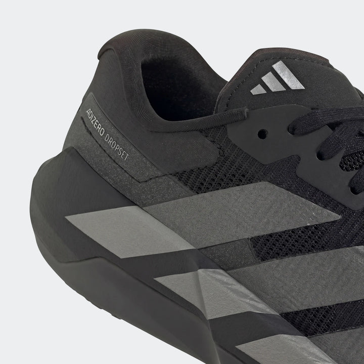A close-up, side view of a black and dark grey Adidas Adizero Dropset Pro training shoe, featuring mesh and striped accents.