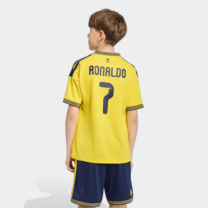 Rear view of a boy wearing the yellow Al Nassr FC 26/27 Home Jersey Kids N&N with 'Ronaldo 7' on the back, paired with navy