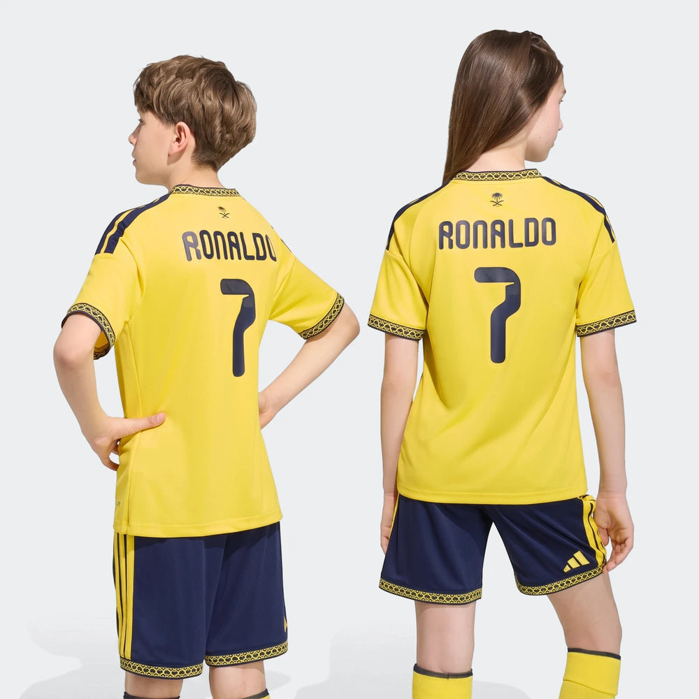 Two children wearing yellow Al Nassr FC 26/27 Home Jerseys with Ronaldo's name and number 7, paired with navy shorts and