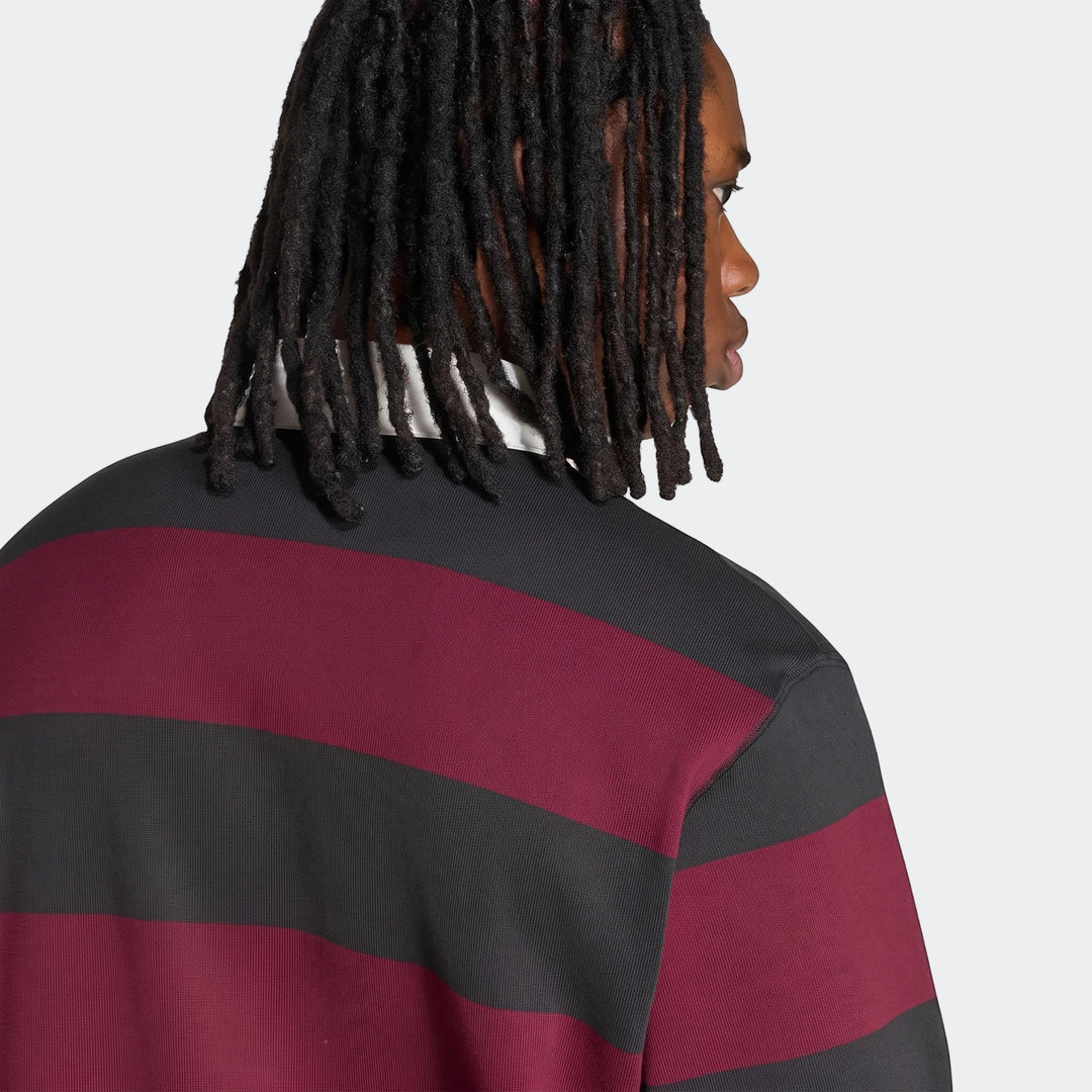 Close-up of a person from the back wearing a black and maroon striped All Blacks Heritage Polo shirt, with dreadlocks