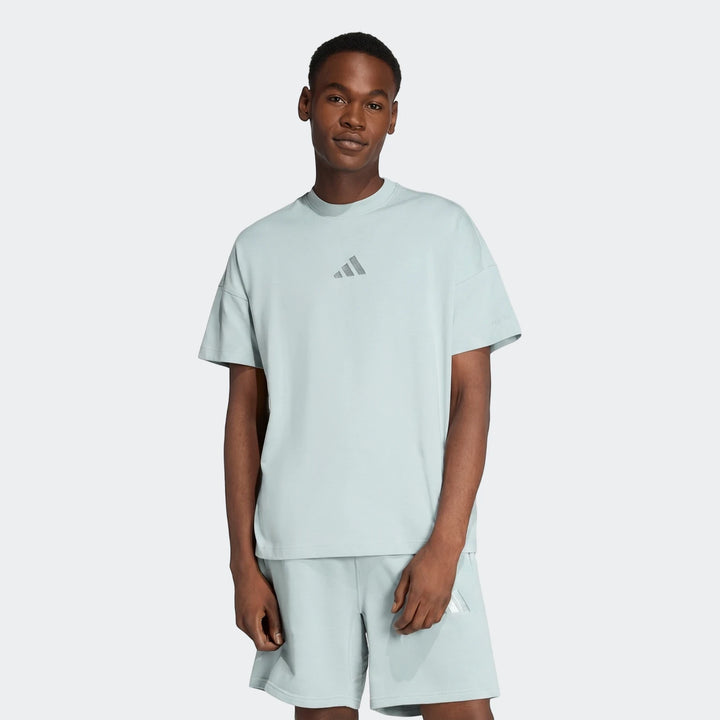 A man models an All Season T-Shirt in light blue, paired with matching shorts, looking directly at the camera.