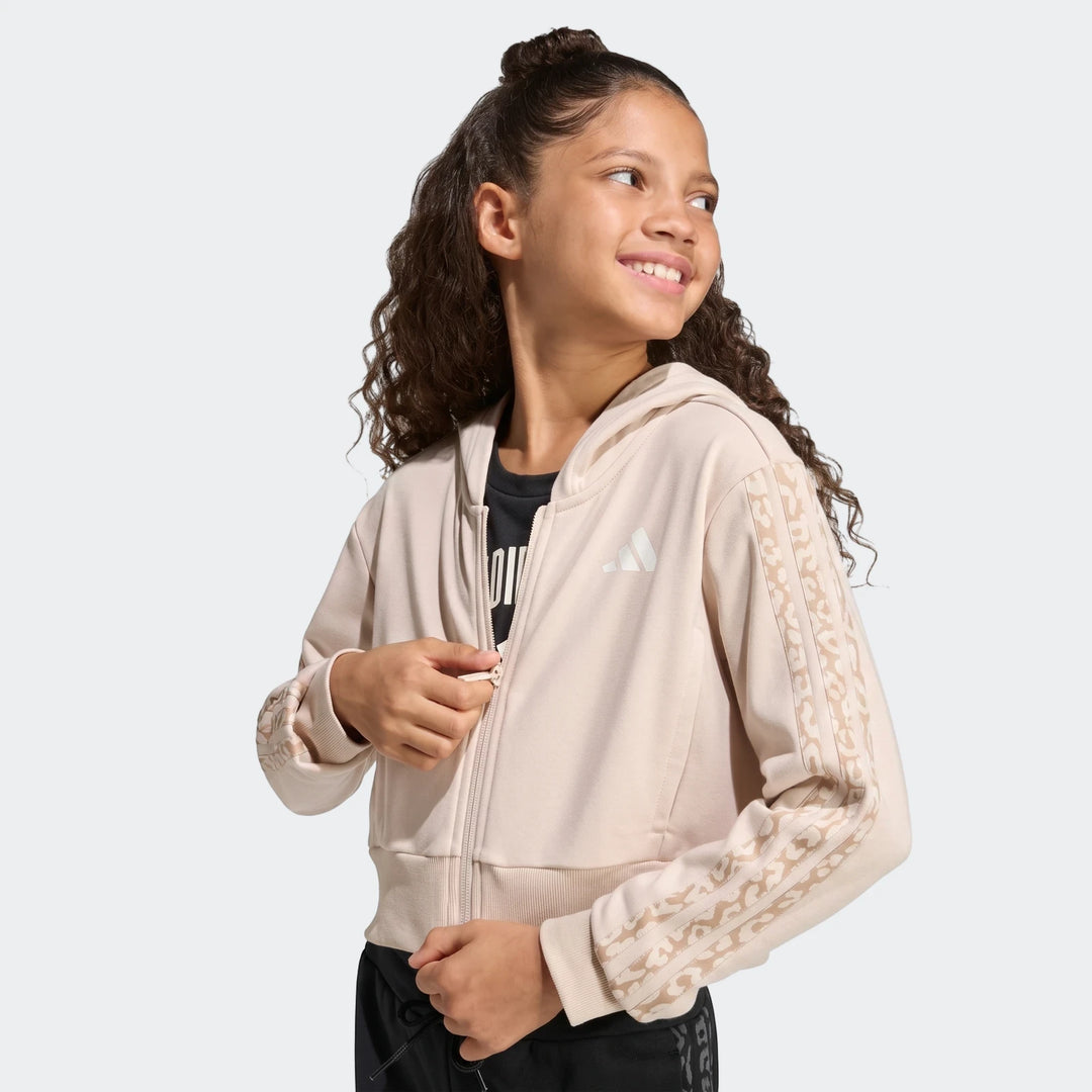Young girl wearing a beige Angled 3-Stripes French Terry Full-Zip Hoodie with leopard print-like stripes on the sleeves.