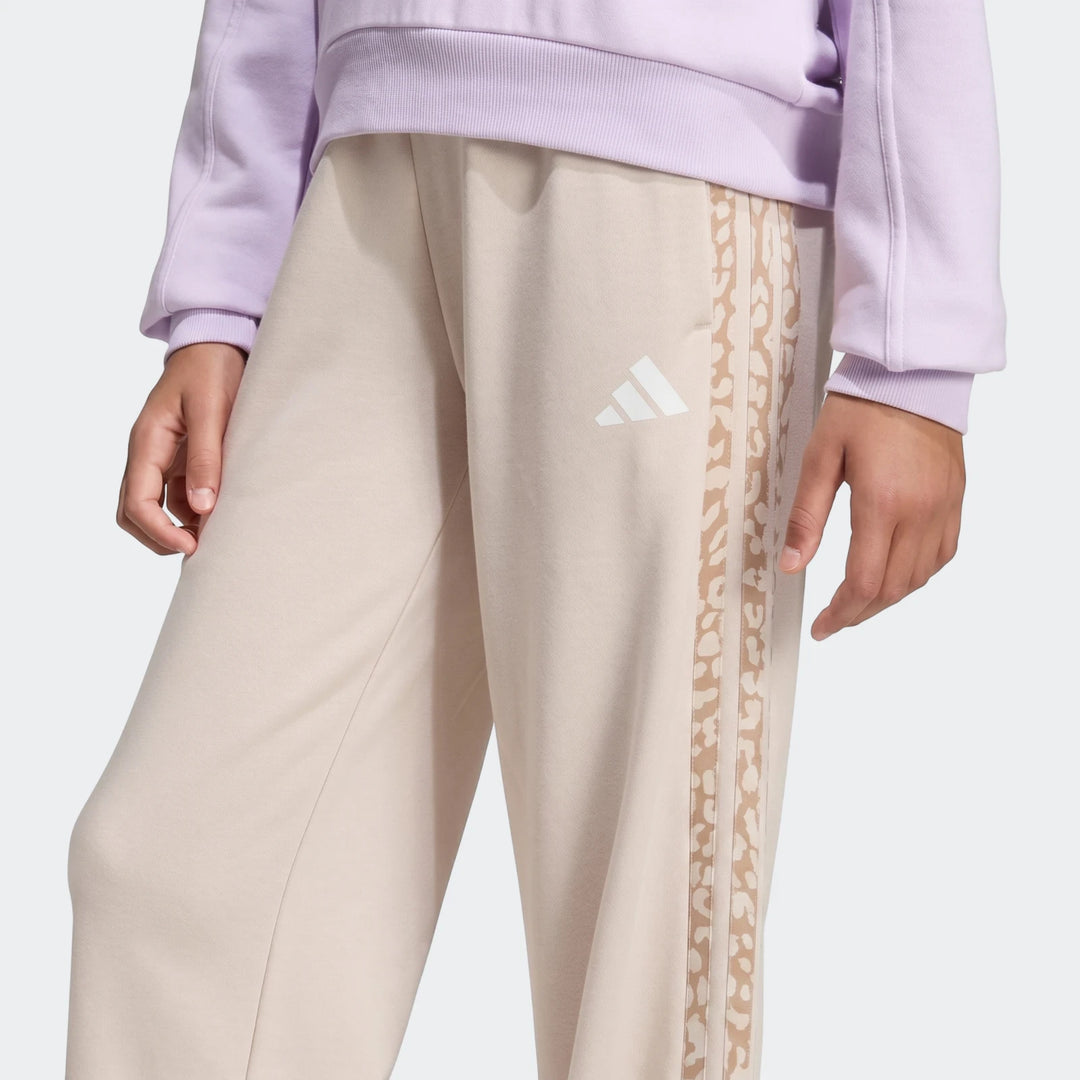 Angled 3-Stripes French Terry Pants in light beige with leopard print Adidas stripes and white logo. Close-up view.