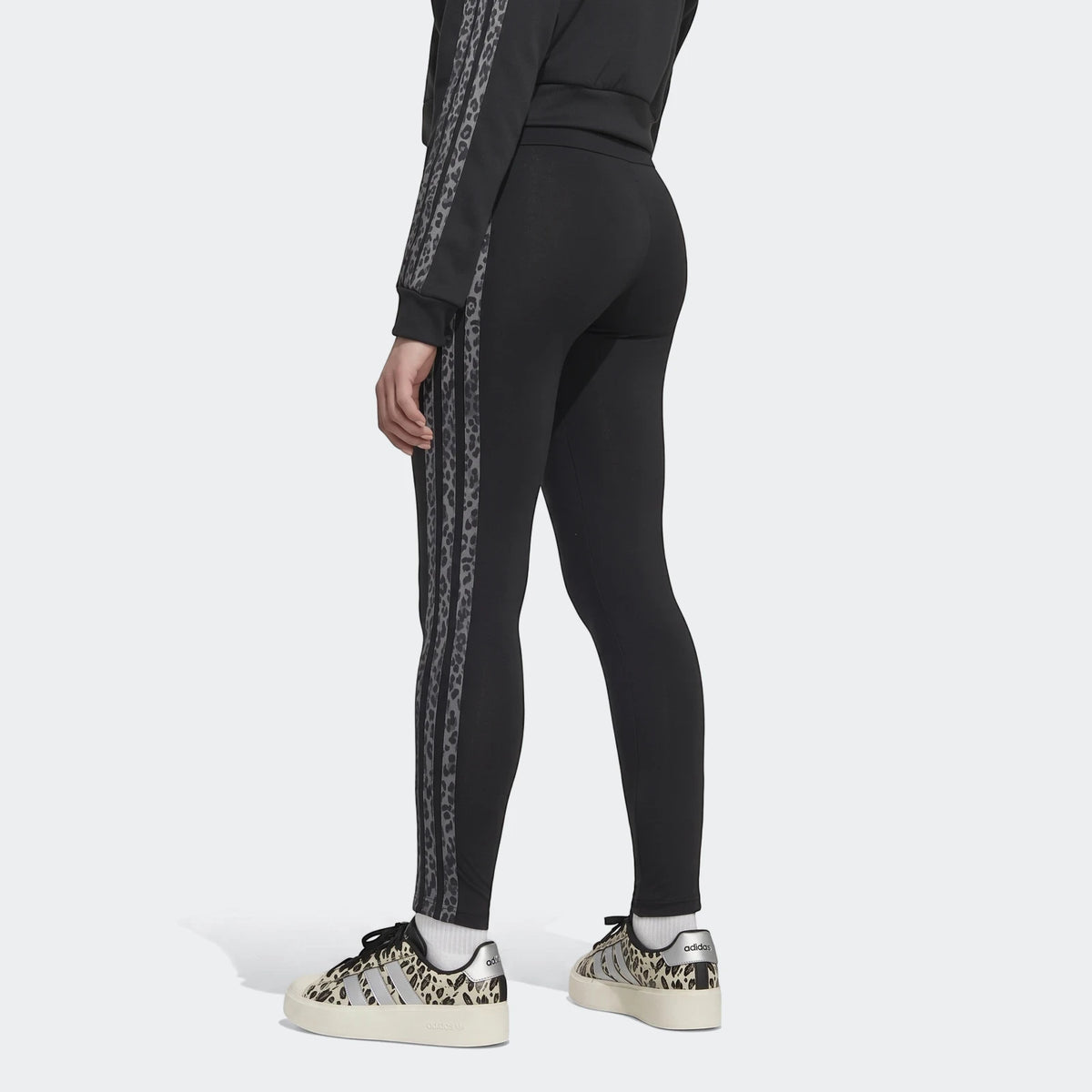 Black Animal Leggings with gray leopard print stripes worn by a model, paired with matching leopard print platform sneakers,