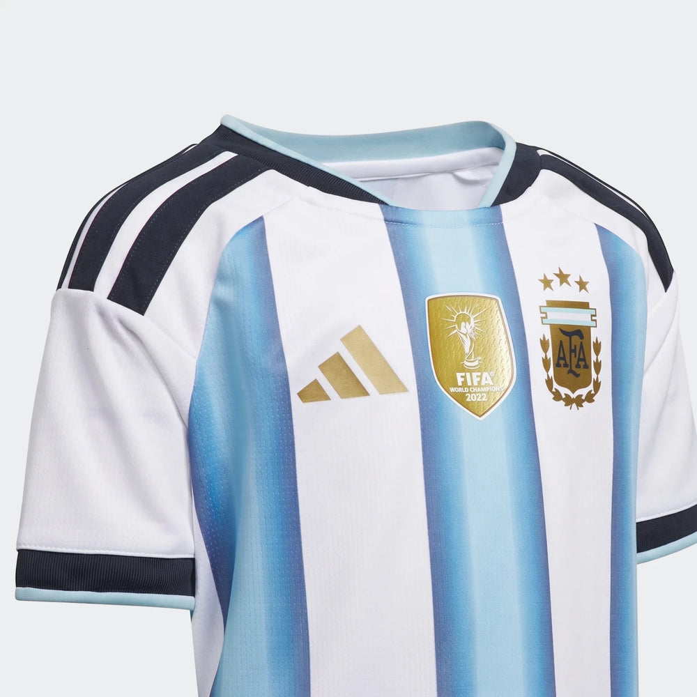 Close-up of the Argentina 26 Home Kids Set jersey, featuring white and light blue stripes, a gold FIFA World Champions 2022