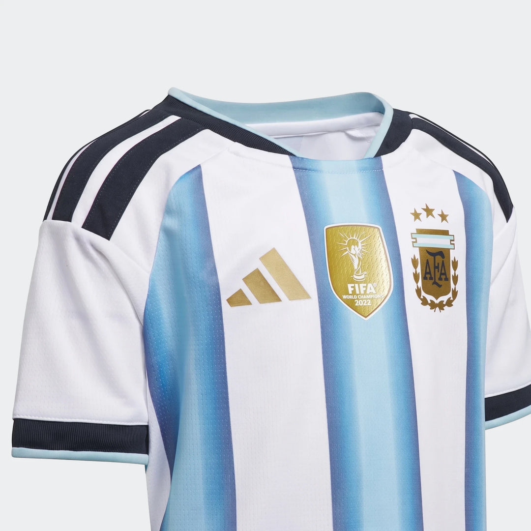 Close-up of the Argentina 26 Home Kids Set jersey, featuring white and light blue stripes, a gold FIFA World Champions 2022