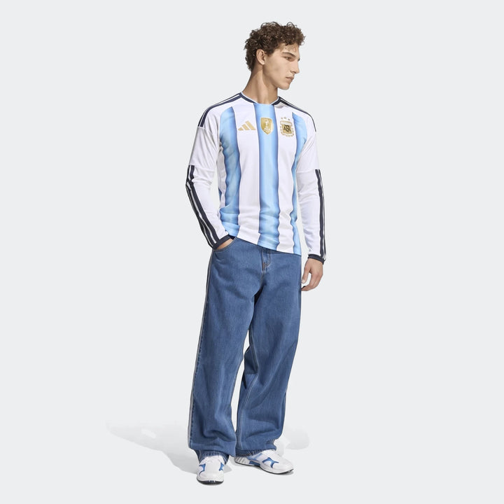 Men's Argentina 26 Home Long Sleeve Jersey featuring blue and white stripes, worn by a model in blue jeans.