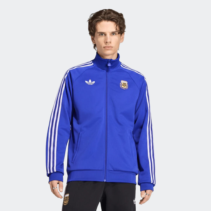 Front view of a male model wearing a blue Adidas Argentina Originals track top featuring white three-stripes on the sleeves