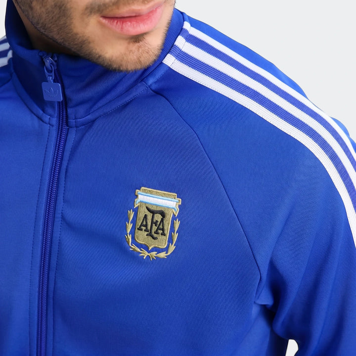 Close-up of a model wearing the blue Argentina Originals Track Top, featuring the AFA crest and white Adidas stripes on the