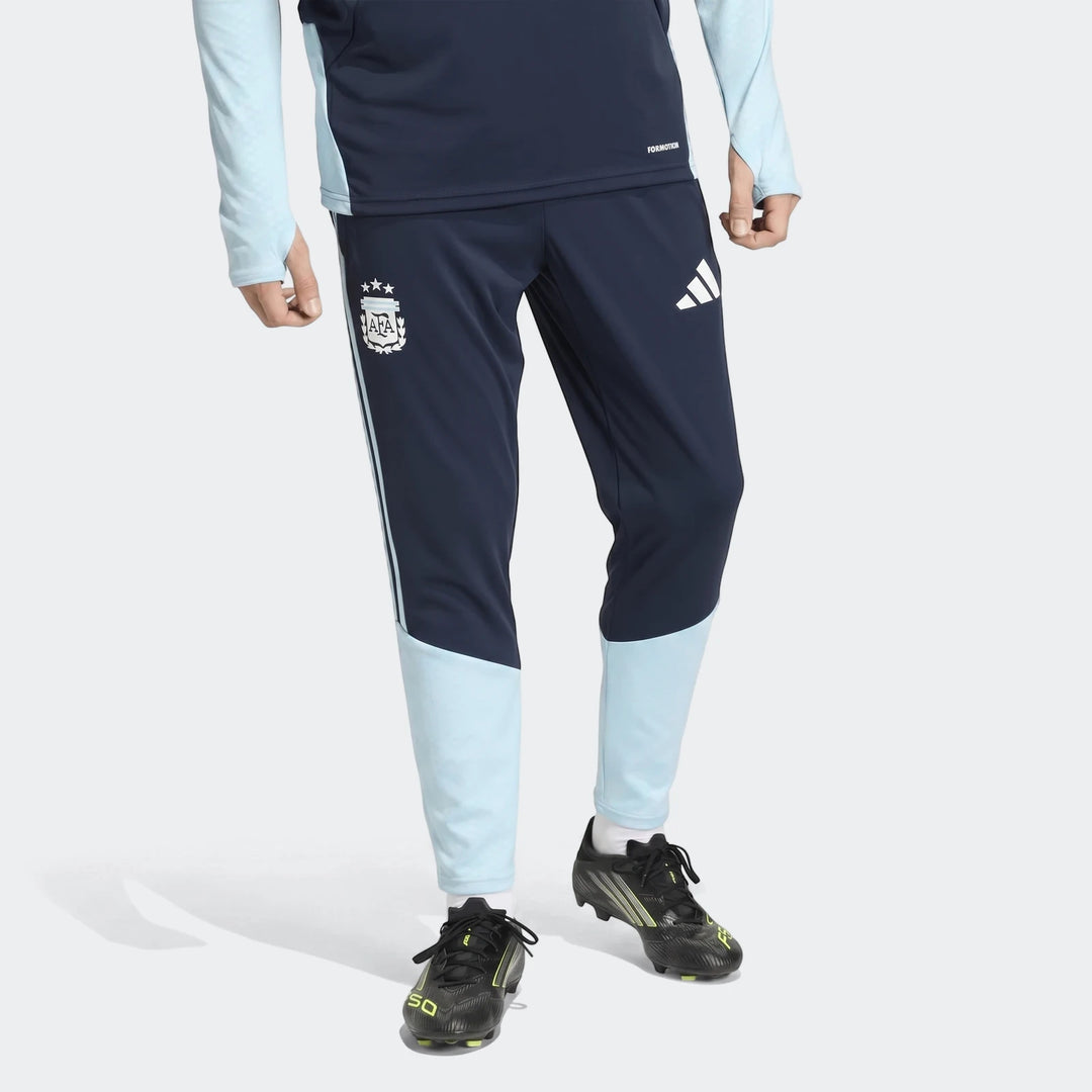 Dark blue and light blue Argentina training pants with AFA crest and Adidas logo, worn by a model with black and yellow