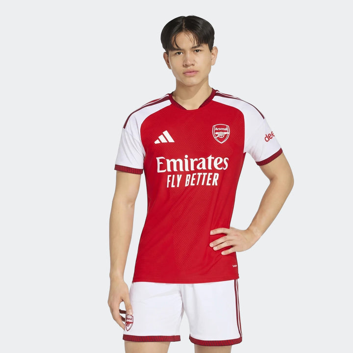 Male model wears Arsenal FC 26/27 home authentic red and white jersey and matching shorts.