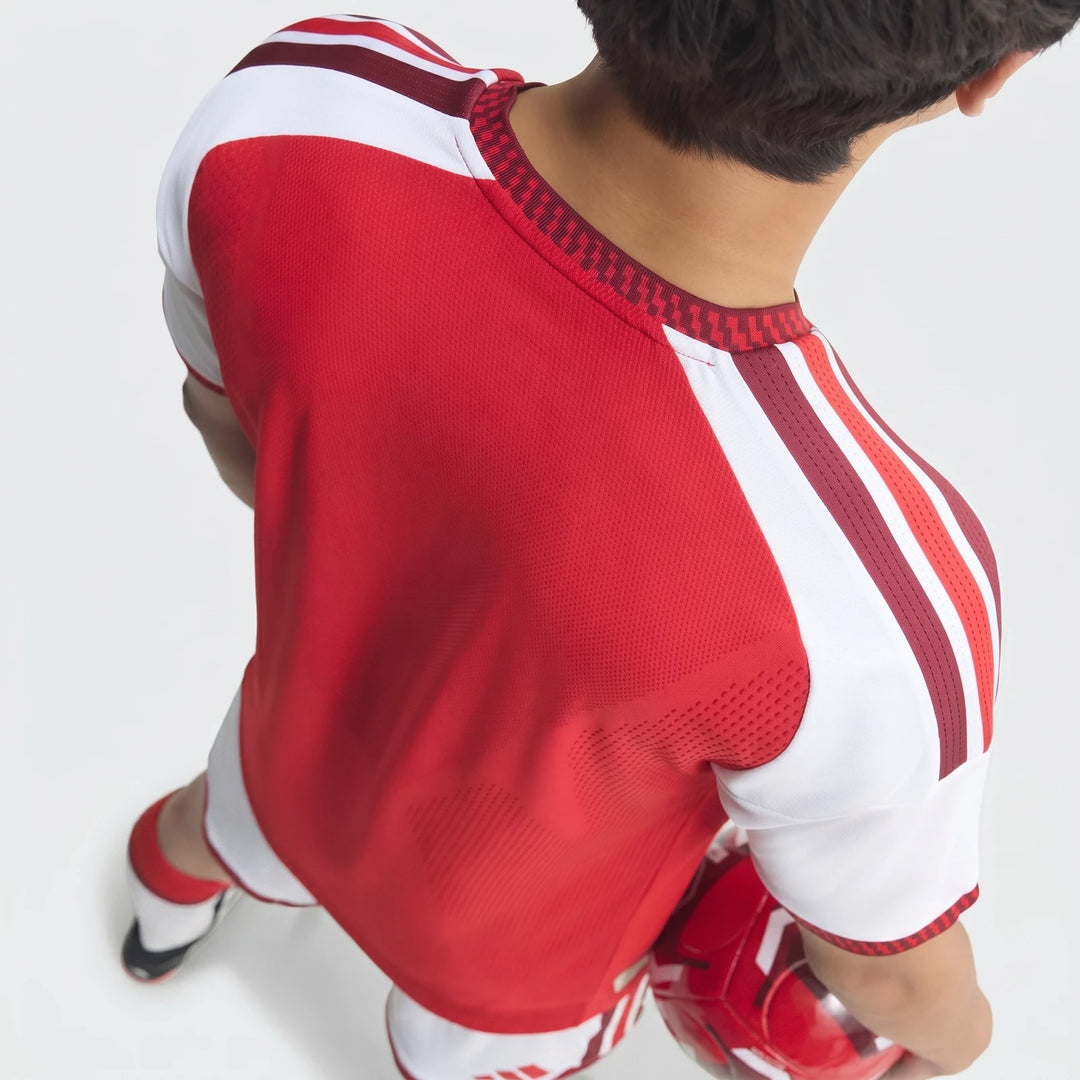 Overhead view of a person wearing the red and white Arsenal Fc 26/27 Home Authentic Jersey, holding a football.