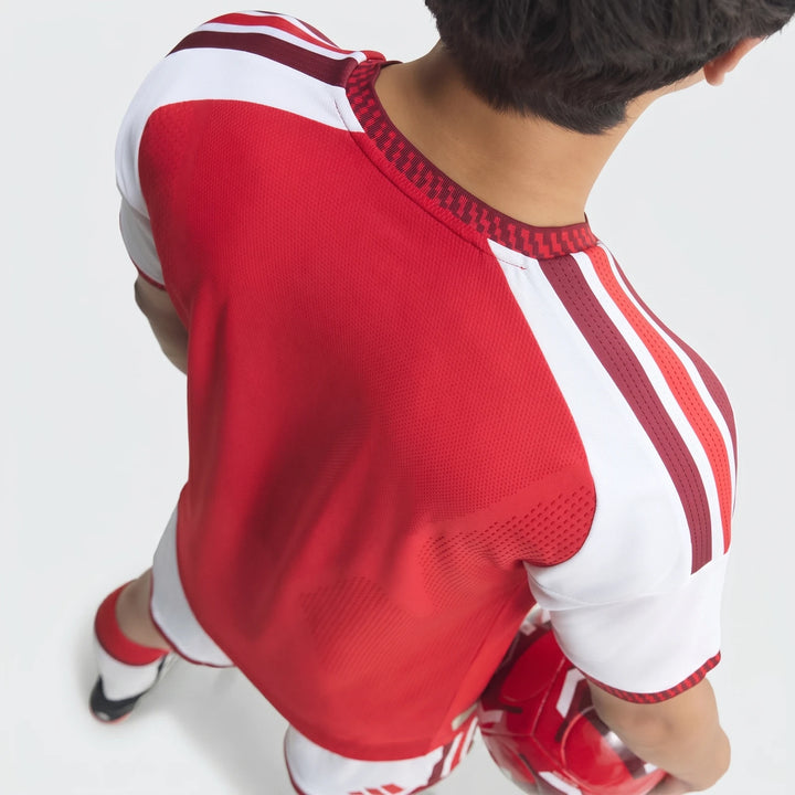 Overhead view of a person wearing the red and white Arsenal Fc 26/27 Home Authentic Jersey, holding a football.