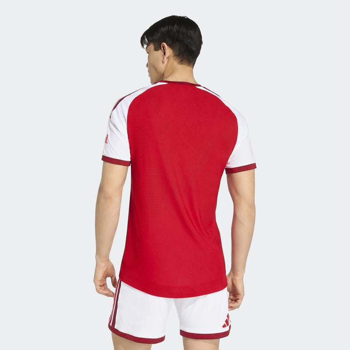 Rear view of a male model wearing the red and white Arsenal Fc 26/27 Home Authentic Jersey and matching shorts.