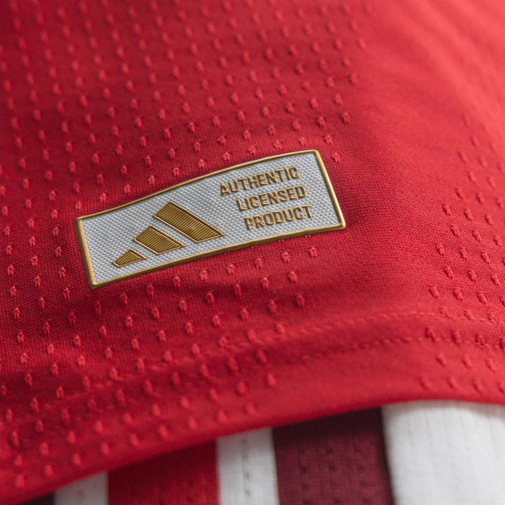 Close-up of the red Arsenal FC 26/27 Home Authentic Jersey, showing the gold Adidas logo on the 'Authentic Licensed Product'