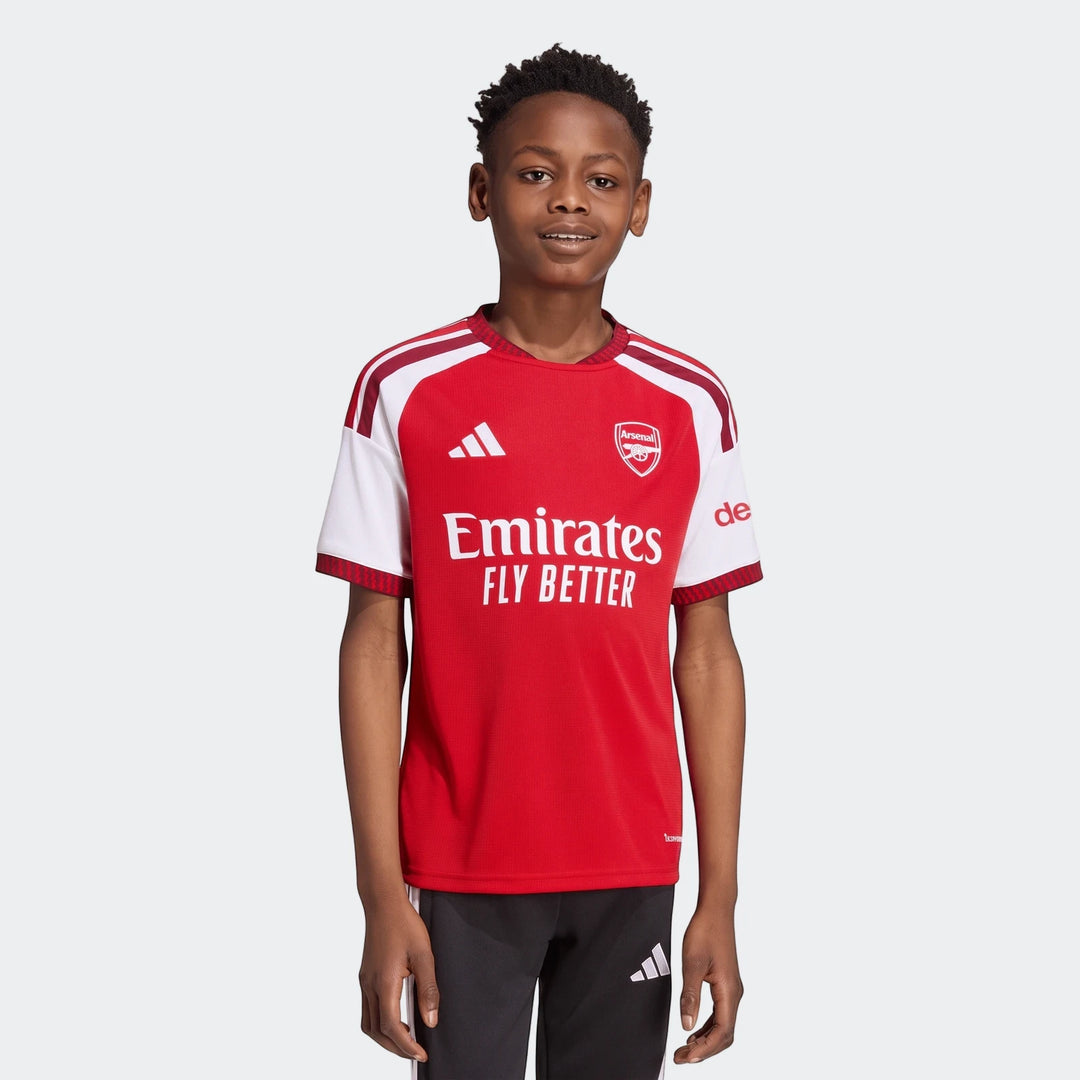 Young boy wearing the red and white Adidas Arsenal FC 26/27 Home Kids Jersey, front view.
