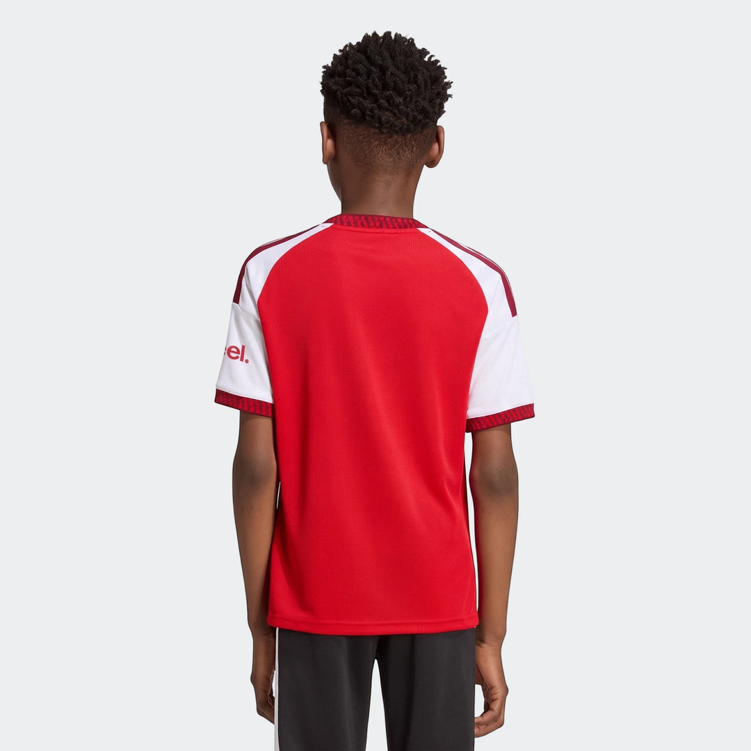 Back view of a young boy wearing the red and white Arsenal Fc 26/27 Home Kids Jersey, featuring raglan sleeves and patterned